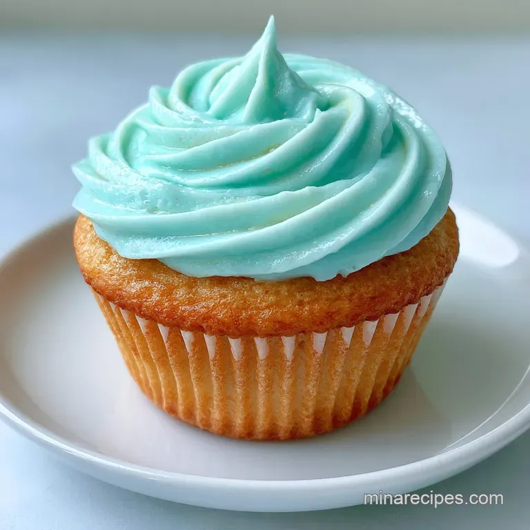 Assorted pastel blue cupcakes arranged on a tiered stand with fresh spring blossoms and a soft linen backdrop.
